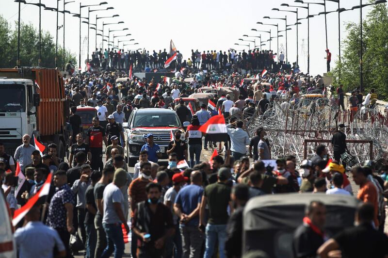 TOPSHOT - Iraqi protesters gather on the capital Baghdad's Al-Jumhuriyah Bridge on October 26, 2019, during an anti-government protest.  Iraqi security forces fired tear gas to clear lingering protesters in Baghdad this morning, after dozens died in a bloody resumption of anti-government rallies to be discussed in parliament. / AFP / -
