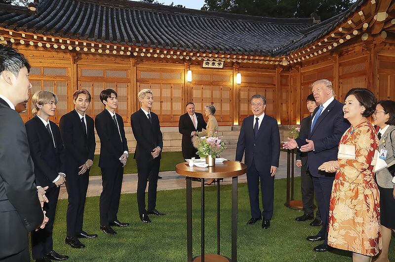 US President Donald Trump talks with South Korean boy band Exo as South Korean President Moon Jae-in stands during a dinner at the presidential Blue House on June 29, 2019 in Seoul, South Korea. Photo by South Korean Presidential Blue House via Getty Images