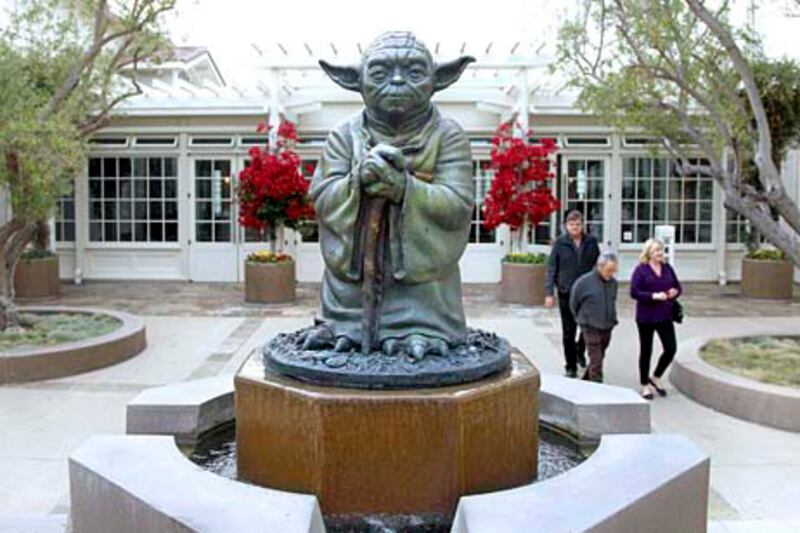 People walk past a fountain showing the Yoda character from the Star Wars movies outside of Lucasfilms headquarters in San Francisco, Tuesday, Oct. 30, 2012. The Walt Disney Co. announced Tuesday that it was buying Lucasfilm Ltd. for $4.05 billion. (AP Photo/Jeff Chiu) *** Local Caption ***  Disney Lucasfilm.JPEG-028e3.jpg