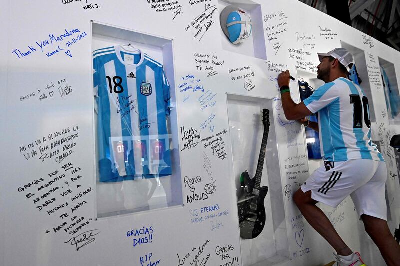 A fan signs his name on a wall to pay tribute to Argentina football legend Diego Maradona at Doha's international airport. AFP