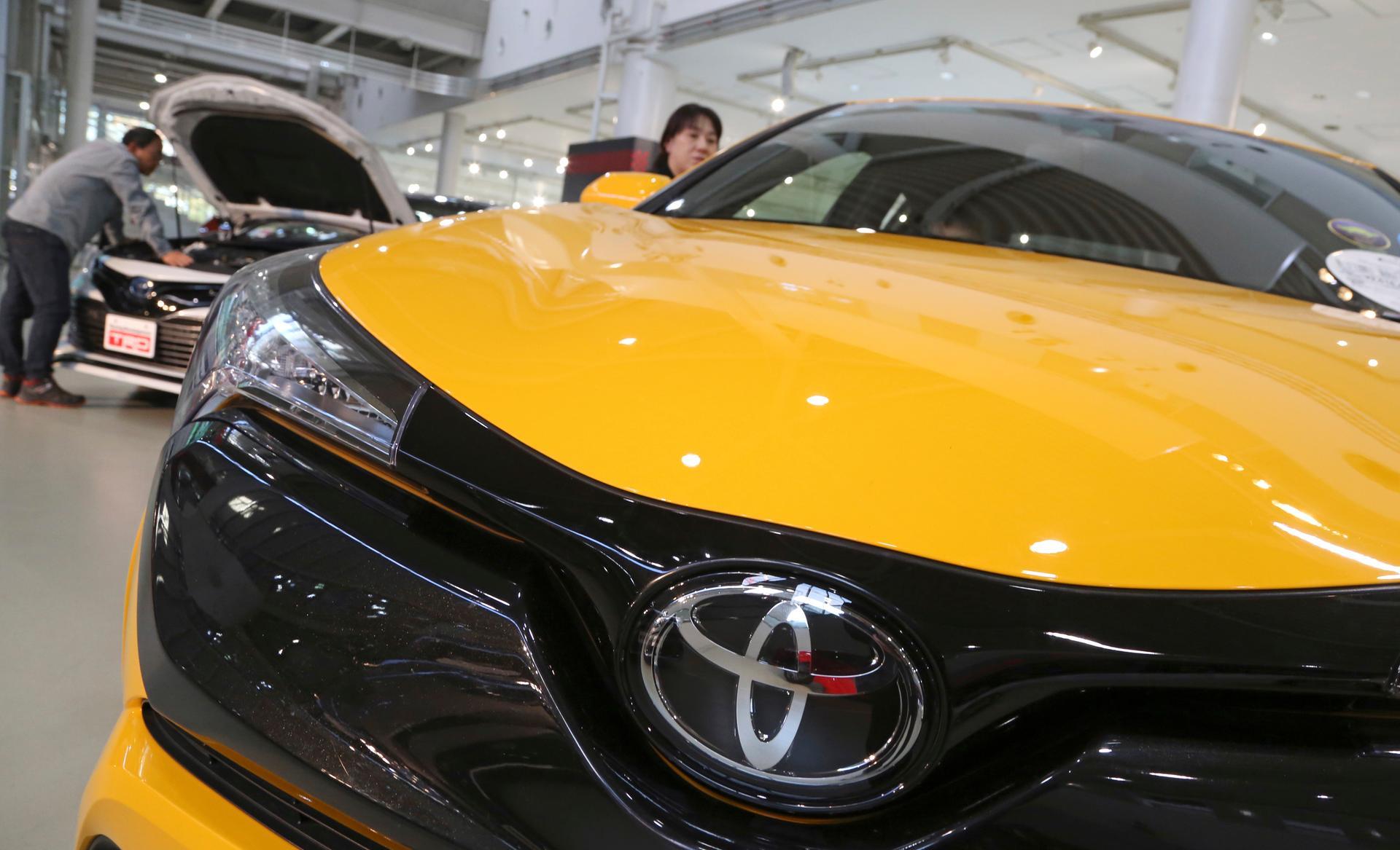 In this Nov. 13, 2017, photo, visitors take a look at Toyota cars at the automaker's showroom in Tokyo. Toyota Motor Corp. has raised its earnings forecast after reporting that its profit surged 28 percent in the last quarter on growing sales and cost cuts. The top Japanese automaker said Tuesday, Nov. 6, 2018, that its July-September profit was 585.1 billion yen ($5.2 billion), up from 458.3 billion yen the year before (AP Photo/Koji Sasahara)