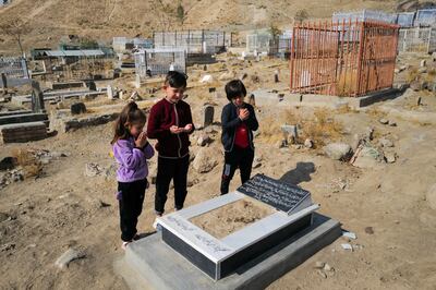 Ada Ahmadi stands with her cousins as they pray by the grave of their relative Farzad, who was a victim of a US drone strike that killed 10 civilians, including seven children, in Kabul, Afghanistan, on November 7, 2021. Reuters