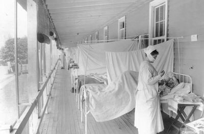 In this November 1918 photo made available by the Library of Congress, a nurse takes the pulse of a patient in the influenza ward of the Walter Reed hospital in Washington.  Historians think the pandemic started in Kansas in early 1918, and by winter 1919 the virus had infected a third of the global population and killed at least 50 million people, including 675,000 Americans. Some estimates put the toll as high as 100 million. By comparison, the AIDS virus has claimed 35 million lives over four decades. (Harris & Ewing/Library of Congress via AP)