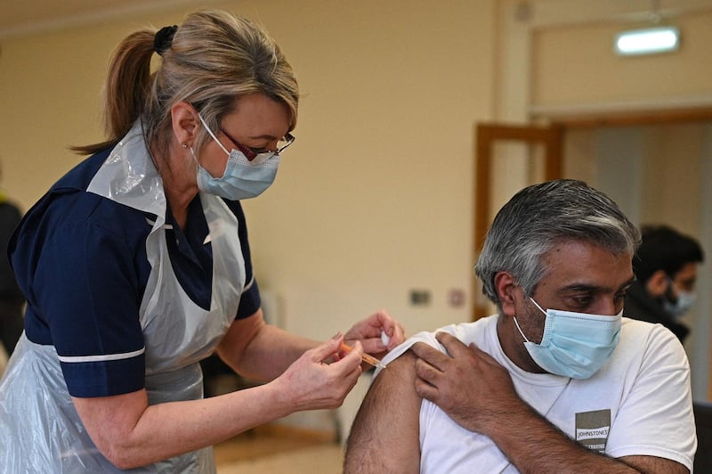 Nurse Maggie Clark administers a dose of the AstraZeneca/Oxford Covid-19 vaccine to a patient at a vaccination centre set up at the Fiveways Islamic Centre and Mosque in Nottingham, central England, on February 22, 2021.  Coronavirus vaccines do not contain pork or make you infertile: a celebrity advertising pitch is striving to counter a worrying lag among certain ethnic minorities affecting Britain's otherwise impressive inoculation campaign. / AFP / Oli SCARFF
