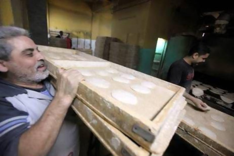 A worker carries trays of dough to an oven in a Cairo bakery. During Mr Morsi’s leadership, the Egyptian pound’s value plunged, making food more expensive.