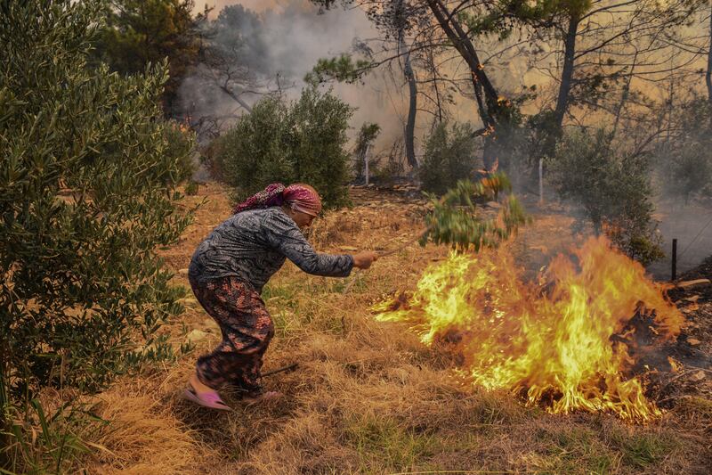 A woman tries to stop an advancing bushfire in Kacarlar village in Antalya, Turkey.