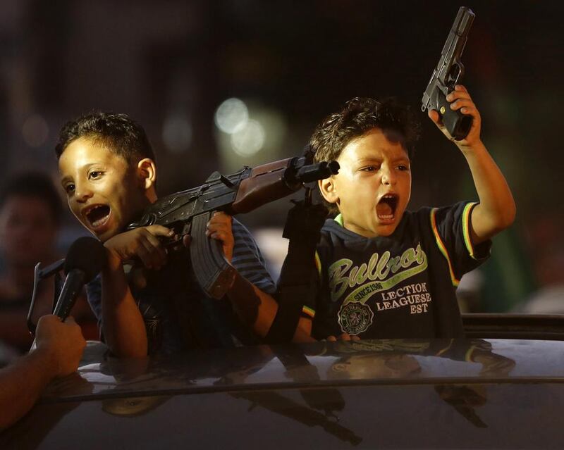 Children hold up guns (one with an empty magazine) from a car as Palestinians gather in the streets to celebrate. Mohammed Abed/ AFP Photo