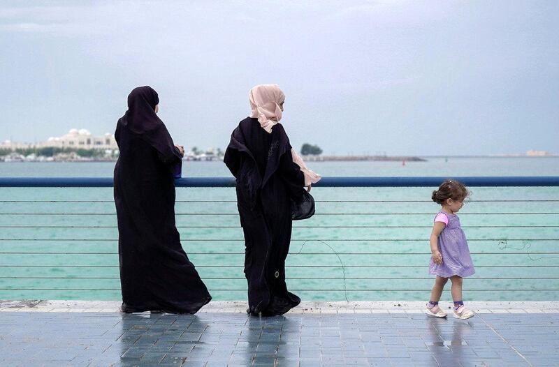 Residents take a walk under leaden skies on Abu Dhabi Corniche. Victor Besa / The National