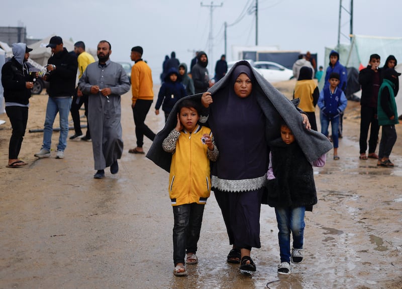 Displaced Palestinians, who fled their houses due to Israeli strikes, walk in heavy rain. Reuters
