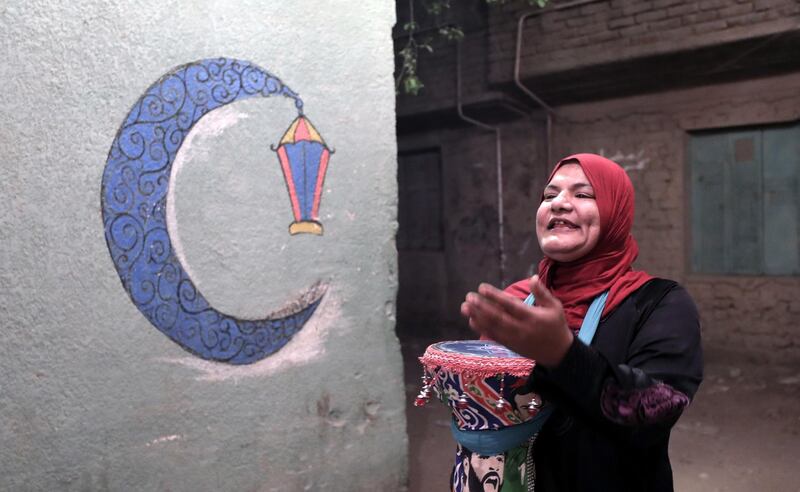 An Egyptian 'Mosahrati', or late night waker, bangs her drums and calls out to the Muslim faithful around the Maadi neighbourhood before dawn in Cairo, Egypt. EPA