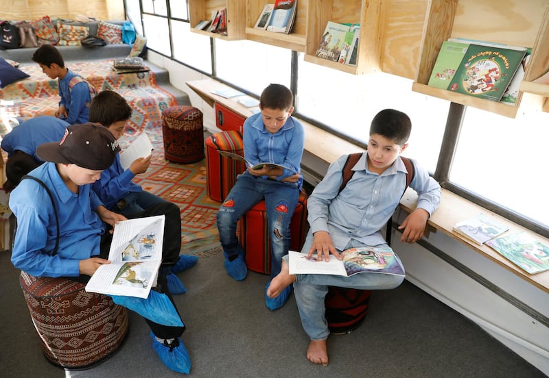Afghan boys read books inside a mobile library bus
