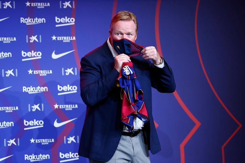 Ronald Koeman holds a Barcelona shirt as he puts on his protective mask during his official presentation as manager. AP Photo