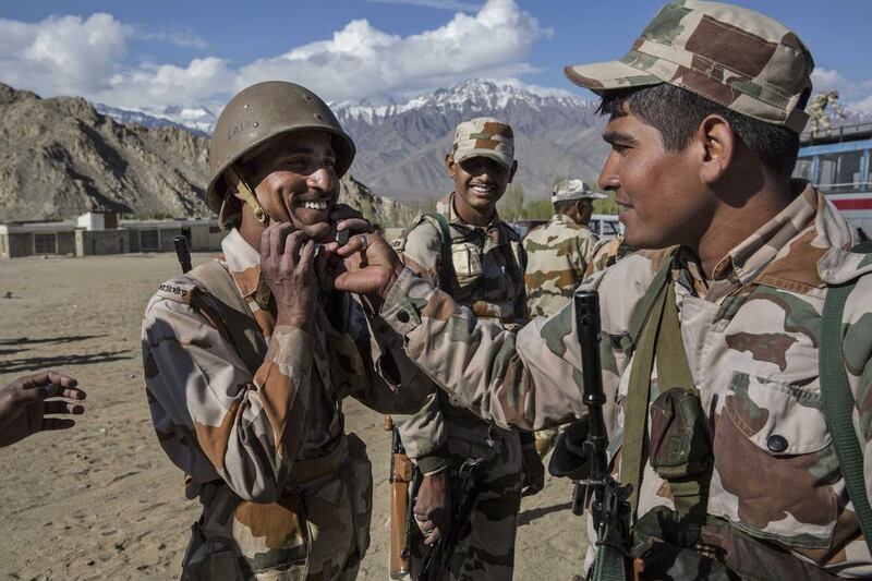 An Indian security force soldier has his helmet adjusted by another as they wait to leave on election duty from a central collection point to head to secure polling stations in Leh, Ladakh, India.