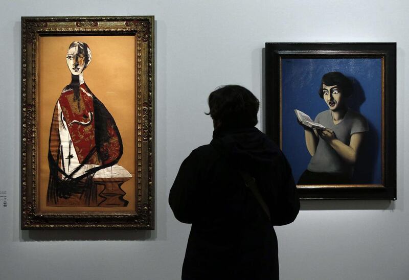 A visitor looks at two paintings, one by Rene Magritte, right, entitled ‘The subdued reader’ (1928) and another by Pablo Picasso entitled ‘Portrait of a woman’ (1928). Francois Guillot/AFP