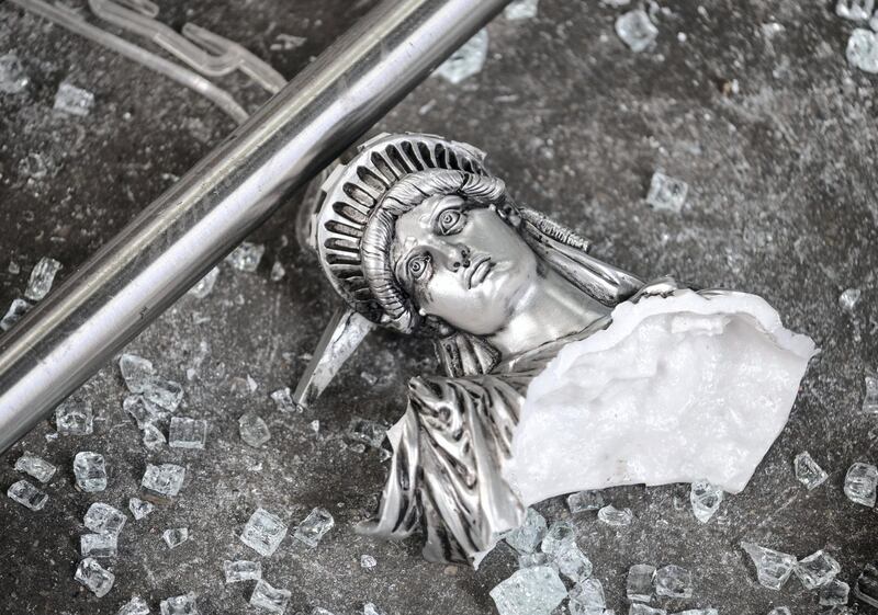 A broken Statue of Liberty figure is seen between glass shatters outside a looted souvenir shop after a night of protest over the death of  an African-American man George Floyd in Minneapolis on June 2, 2020 in Manhattan in New York City. - New York's mayor Bill de Blasio yesterday declared a city curfew from 11:00 pm to 5:00 am, as sometimes violent anti-racism protests roil communities nationwide. Saying that "we support peaceful protest," De Blasio tweeted he had made the decision in consultation with the state's governor Andrew Cuomo, following the lead of many large US cities that instituted curfews in a bid to clamp down on violence and looting. (Photo by Johannes EISELE / AFP)