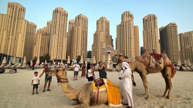 Tourists take photos with camels on the beach at Jumeirah Beach Residence in Dubai. New data shows the emirate is on track for another standout performance in tourism this year. Reuters