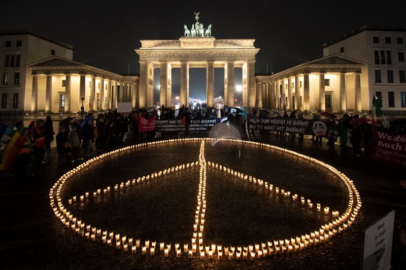 Activists place candles forming the peace sign in front of the Brandenburg Gate, in Berlin. AP
