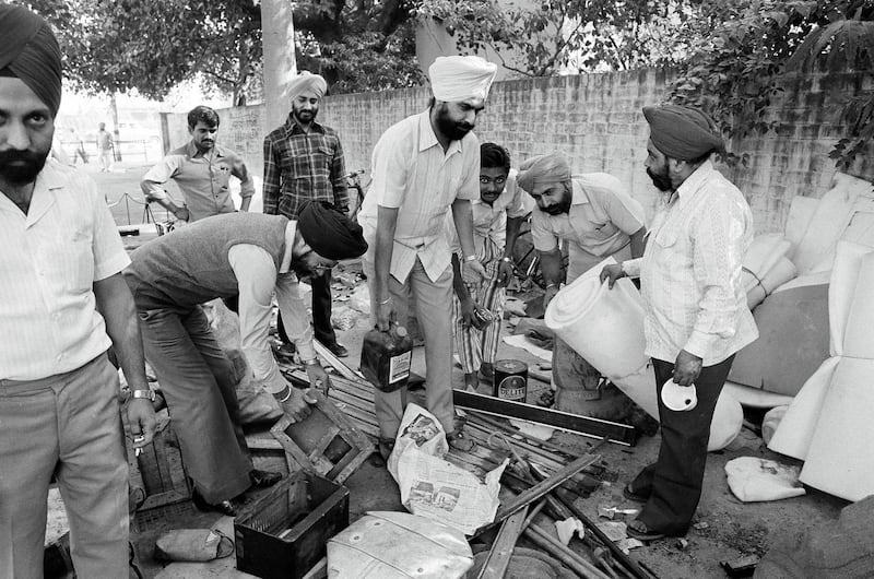 Members of the Indian Sikh community, whose house were attacked, burned and looted the past days by mobs of Hindus are seen as they collect their looted property in a Delhi police station, Nov. 6, 1984. Life is returning to normal after heavy riots that followed the assassination of Prime Minister Indira Gandhi. (AP Photo/Peter Kemp)