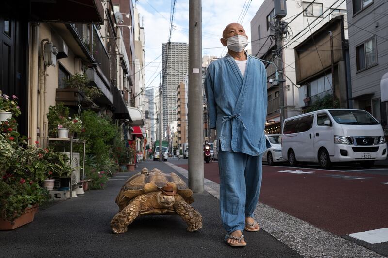Hisao Mitani with an African tortoise, which he named Bon-Chan, on the street in Tokyo, Japan. Bon-chan, 26, is cared for by 69-year-old funeral director Mr Mitani and has become an internet sensation after starring in a viral TikTok video that has gained more than seven million views since it was released. Getty Images