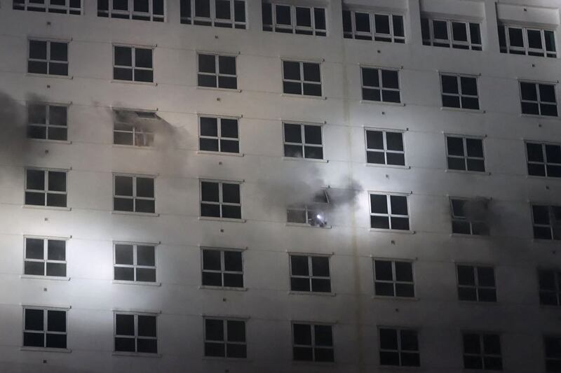 People flash lights from a window during the fire. AFP