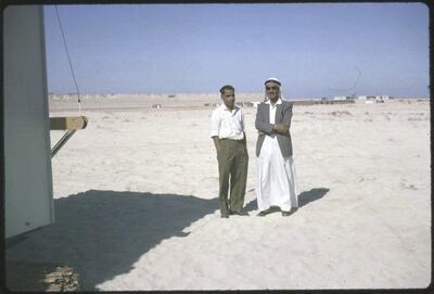 Jebel Dhana, Abu Dhabi 1963 
Two employees of the British Bank of the Middle East, Abu Dhabi taken on a construction site in Jebel Dhana, where Wimpeys were building a new oil terminal. On the left is, Juveira , a clerk and on the right, Ali Bhutti, who was a cashier and an Abu Dhabi local.
 
[Note - at this time there were very few locals, who had had an education and it was certainly not common to find many who spoke English. Shortly after this photograph was taken, Bhutti was summoned to the Palace by the Ruler, Sheikh Shakbhut and appointed the new Postmaster of Abu Dhabi. The Ruler had decided that he would take over the running of the Postal Administration from the British Goverment. Although Bhutti enjoyed his work with the Bank and his prospects with them were good in those days you did not refuse the wishes of the Ruler!] Photo by David Riley