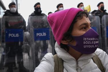 A protester wears a face mask written 'Apply Istanbul Convention' as she shouts slogans while Turkish riot police block the way during a protest against Turkey's decision to withdraw from the Istanbul Convention on March 31, 2021.