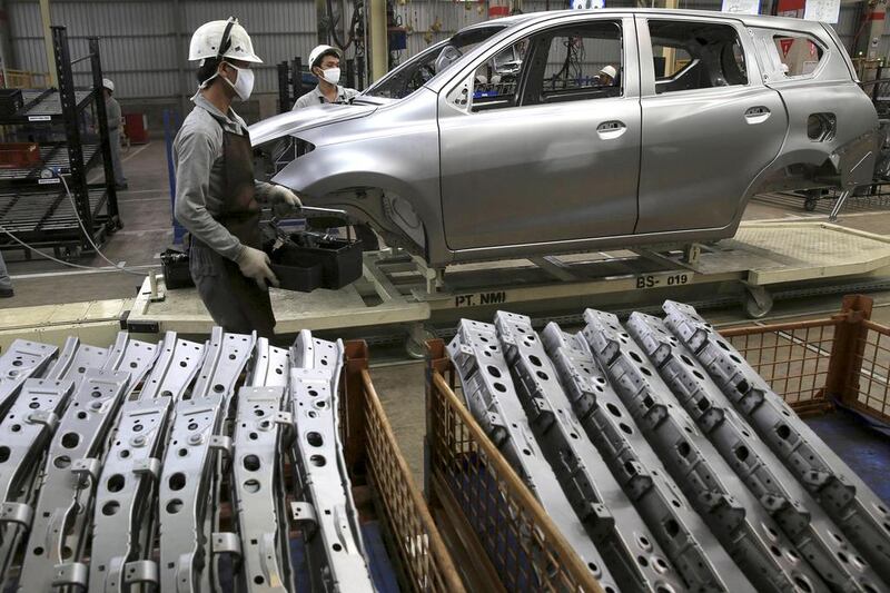 Workers stand near a vehicle frame at an assembly line of Datsun Go+. Beawiharta / Reuters