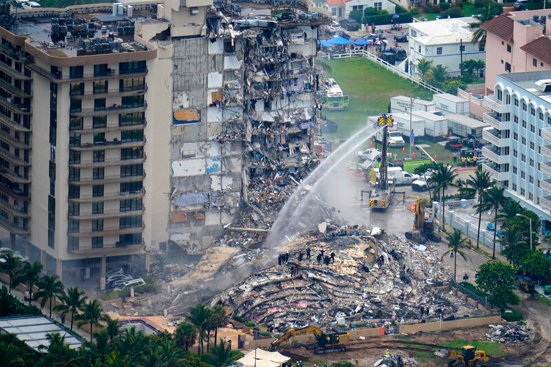 Water is sprayed on the debris to douse any remaining fire. ​AP