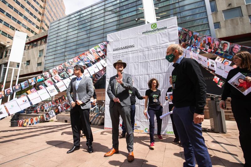 Donald Pols, director of MilieuDefensie, center, makes a statement to the media near a photo display of claimants during the Dutch environmental organisation's case against Royal Dutch Shell Plc emission hearing, outside the Palace of Justice courthouse in The Hague, Netherlands, on Wednesday, May 26, 2021. The case against Shell was brought by local environmental group MilieuDefensie who accuse the company of violating human rights by not adhering to the Paris Agreement’s aim of limiting the average increase in global temperatures to less than 1.5 degrees Celsius. Photographer: Peter Boer/Bloomberg