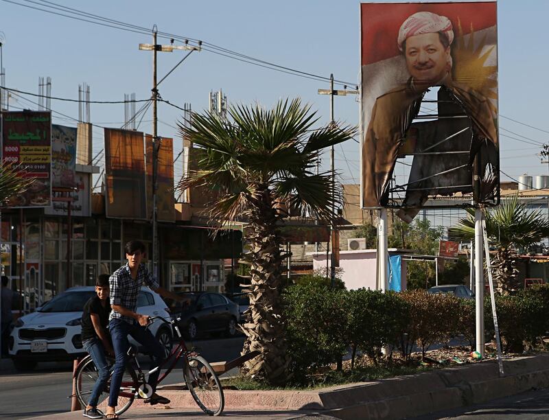 A burned poster of Massoud Barzani, the President of Iraq's autonomous Kurdish region, is displayed in front of the abandoned building of Kurdish security forces in Kirkuk, Iraq, Thursday, Oct. 19, 2017. A Baghdad court has issued an arrest warrant for the vice president of Iraq's Kurdish region for saying Iraqi forces were "occupying" the disputed Kirkuk province. (AP Photo/Khalid Mohammed)
