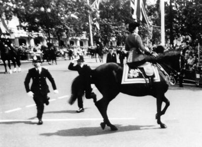 Queen Elizabeth II calming her horse Burmese while policemen spring to action after shots were heard as she rode down the Mall during Trooping the Colour in June 1981.