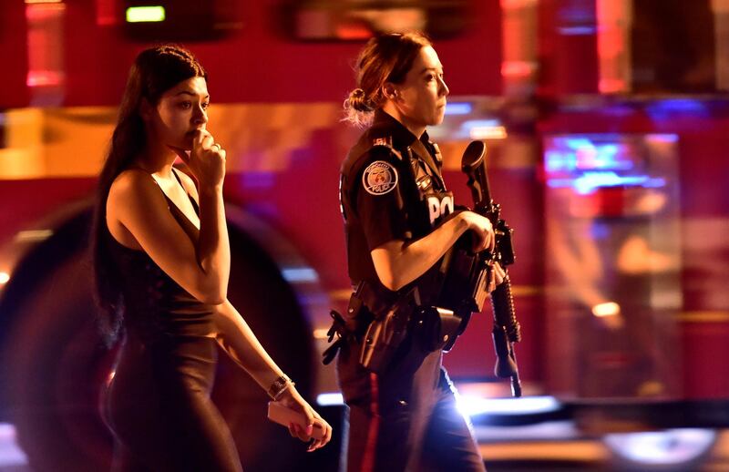 A police officer escorts a civilian away from the scene of a shooting in Toronto. AP Photo