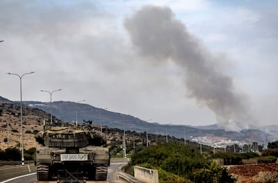 An Israeli Merkava tank is deployed as smoke billows on the hills in the northern region of Kiryat Shmona near the border with Lebanon on Monday. AFP