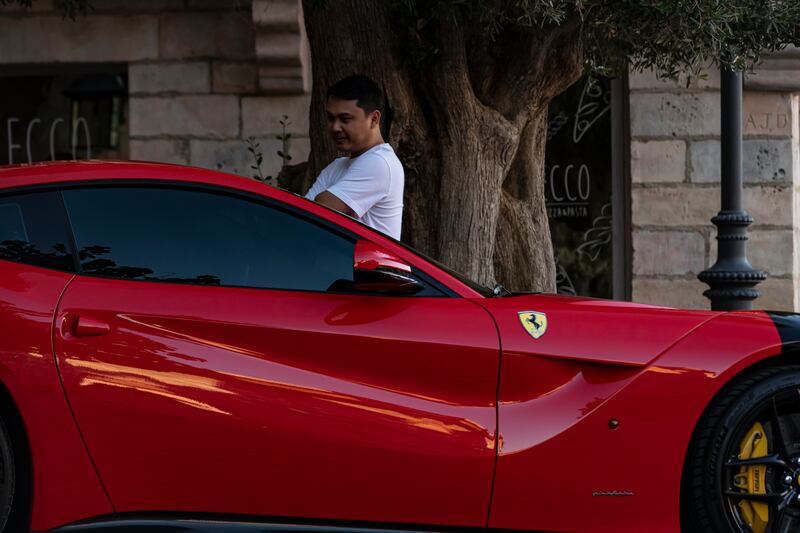 A man admires a Ferrari during a super car parade at Riverland, part of Dubai Parks and Resorts. Antonie Robertson / The National