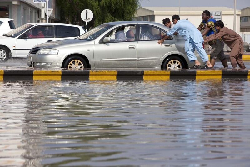 Motorists and pedestrians get to grips with the flooding on a street behind Sharjah City Centre. Antonie Robertson / The National 