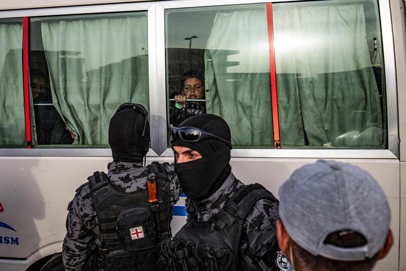 A child looks through the window of a bus at security officers during the handover of 34 orphaned children of suspected ISIS fighters by Syrian Kurdish officials to a Russian delegation in the city of Qamishli, north-east Syria. AFP