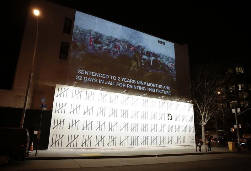 epa06607205 A mural painted by Banksy, the anonymous British street artist, protests the imprisonment of Zehra Dogan on the Bowery in New York City, USA, 15 March 2018. The 70-foot-long mural was unveiled on Thursday, and it protests the imprisonment of the Turkish artist and journalist Zehra Dogan, who was sentenced last March for painting the destruction of a Turkish town, with the country's flag flying over rubble.  EPA-EFE/JASON SZENES