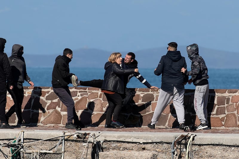 Locals, who prevent migrants on a dinghy from disembarking at the port of Thermi, beat a journalist, as a woman tries to stop them, on the island of Lesbos, Greece. REUTERS