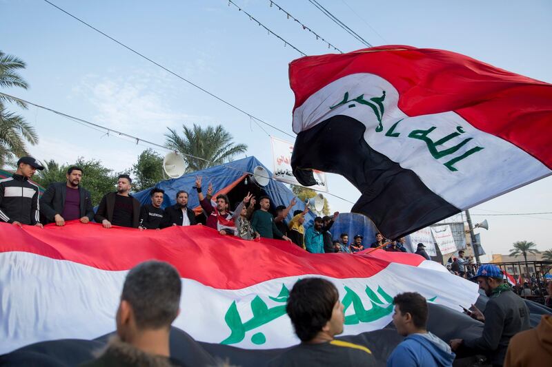 Activists chant anti-government slogans and fly big Iraqi flags at Tahrir square, in Baghdad, Iraq, Tuesday, Dec. 10, 2019. Thousands of Iraqi protesters celebrated the two-year anniversary of the defeat of the Islamic State group amid protests and public anger. (AP Photo/Nasser Nasser)