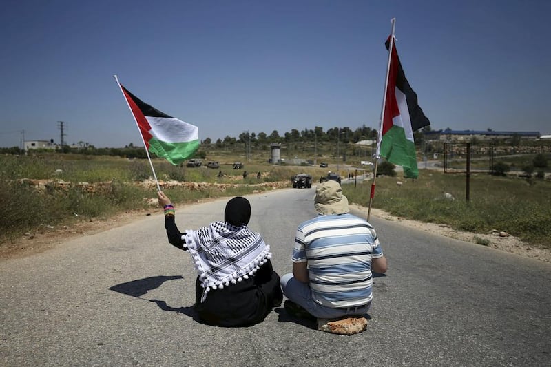 Palestinian protesters wave flags as Israeli troops take position during a protest against Jewish settlements in the West Bank village of Nabi Saleh, near Ramallah.  Reuters