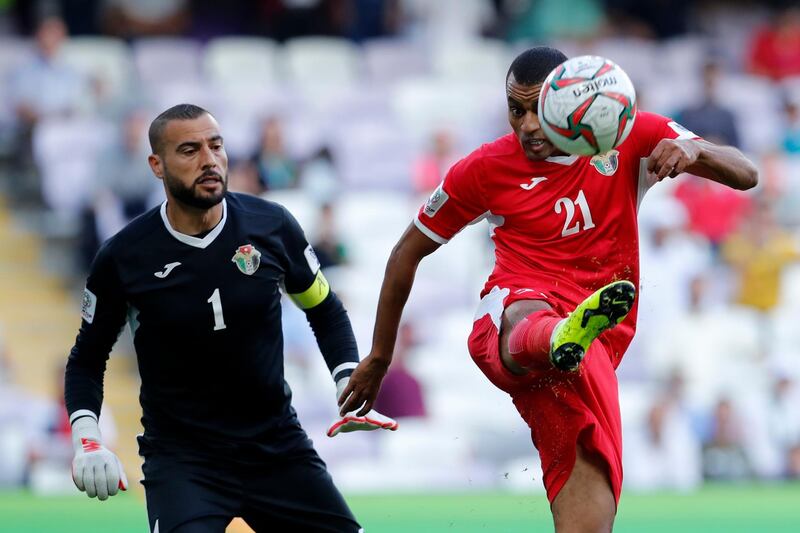 Jordan's defender Salem Al Ajalin, right, clears the ball next to goalkeeper Amer Shafi. AP Photo