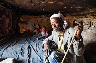 A man and children sit in a cave where a Yemeni family has sought refuge due to poverty and lack of housing, west of the suburbs of Yemen's third-city of Taez on December 2, 2020.  / AFP / AHMAD AL-BASHA
