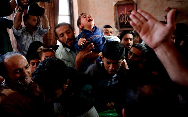 The son of Islam Herzallah, 28, who was shot by Israeli troops east of Gaza City and transported to a hospital where he died, mourns over his father's body during his funeral in Gaza City. Thomas Coex / AFP