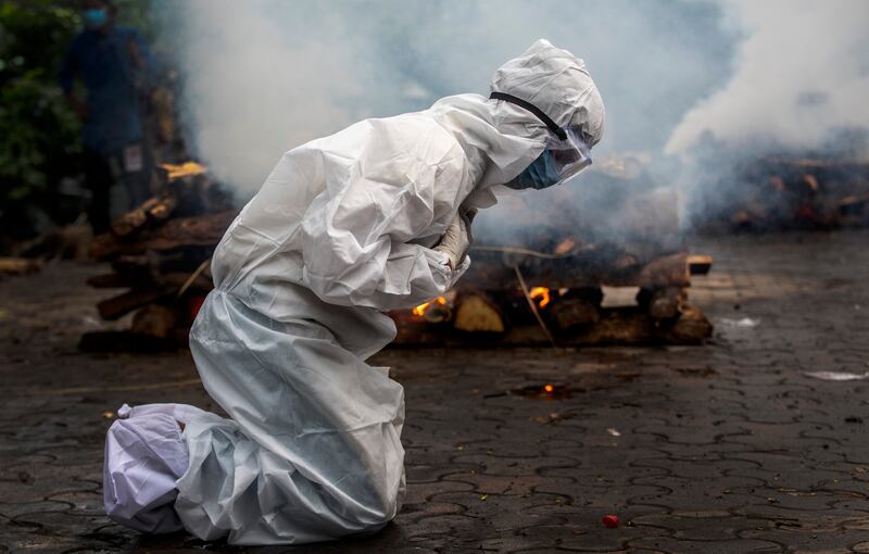 A woman in Gawahati, India, prays before the cremation of a relative, one of more than 400,000 people to die from Covid-19 in the country since the the pandemic began.