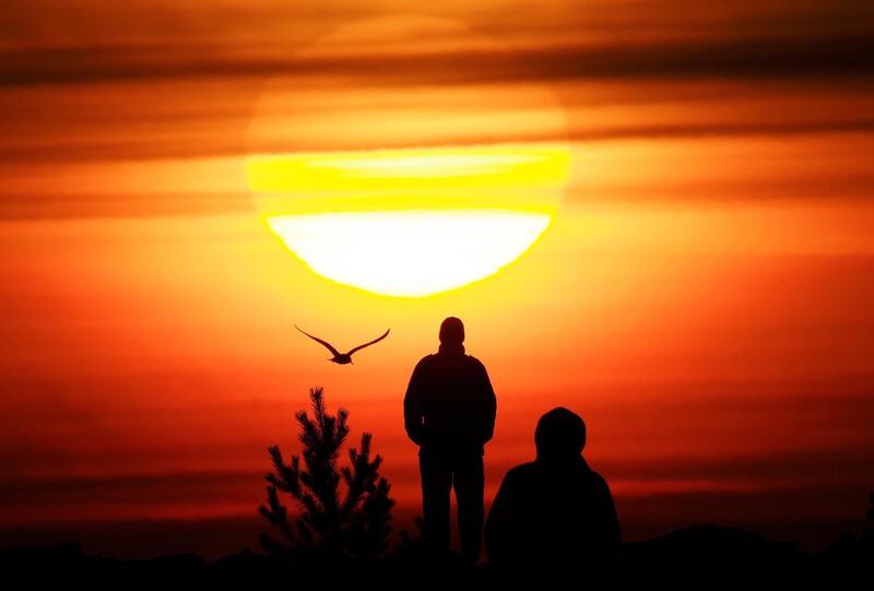 People watch the sunset over the Finnish Gulf coast in St Petersburg, Russia. AP