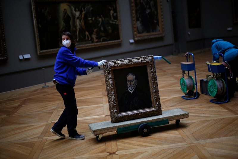 A worker transports a painting called 'Portrait of Antonio de Covarrubias y Leiva' by Spanish painter El Greco in the Louvre on February 9, 2021. AP