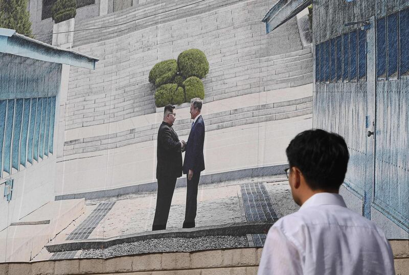 TOPSHOT - A man walks past a giant banner showing a picture of the summit handshake between South Korean President Moon Jae-in and North Korean leader Kim Jong Un, at Seoul City Hall on September 13, 2018. South Korean President Moon Jae-in will fly to North Korea's capital on September 18, for a third summit with the North's leader Kim Jong Un as US efforts to dismantle Pyongyang's nuclear arsenal have stalled. / AFP / Jung Yeon-je
