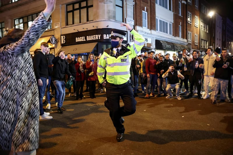 A policeman dances with people partying along a street in Soho, Central London, as Britain eases coronavirus restrictions. Reuters