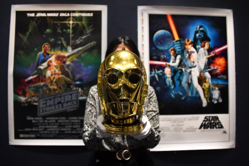A Sotheby's employee holds a C-3PO helmet of 1983 as part of the Star Wars auction in London. Sotheby's will now host its second sale dedicated to 'Star Wars' collectibles, titled 'Star Wars Online'. AP Photo