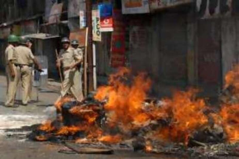 Policemen stand guard besides material from a shop set afire by supporters of hard-line Maharashtra Reconstruction Party in Kalyan, near Mumbai, India, Wednesday, Oct. 22, 2008.  Curfew has been clamped in the town where the founder of the party Raj Thackeray facing charges of inciting violence against migrant workers in India's financial capital, is being held under arrest. On Sunday, dozens of his supporters attacked students from northern India who had traveled to Mumbai on the west coast of India to apply for jobs on the railways. (AP Photo) *** Local Caption ***  MUM102_India_Mumbai_Migrants.jpg